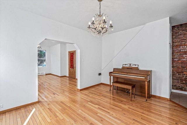 misc room with light hardwood / wood-style floors, a chandelier, and a baseboard heating unit