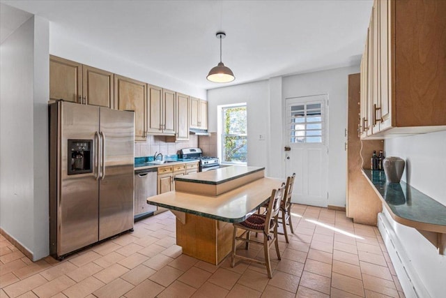 kitchen with hanging light fixtures, appliances with stainless steel finishes, a center island, a breakfast bar, and decorative backsplash