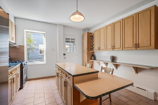 kitchen featuring pendant lighting, stainless steel gas range, a kitchen island, a breakfast bar, and light tile patterned floors