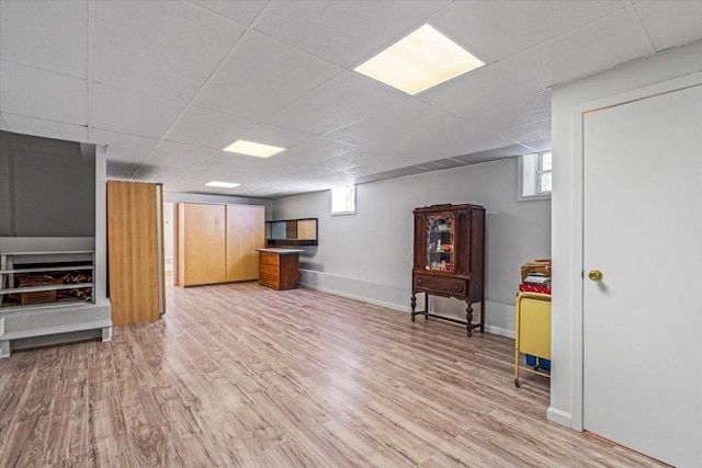 basement featuring light hardwood / wood-style flooring and a paneled ceiling