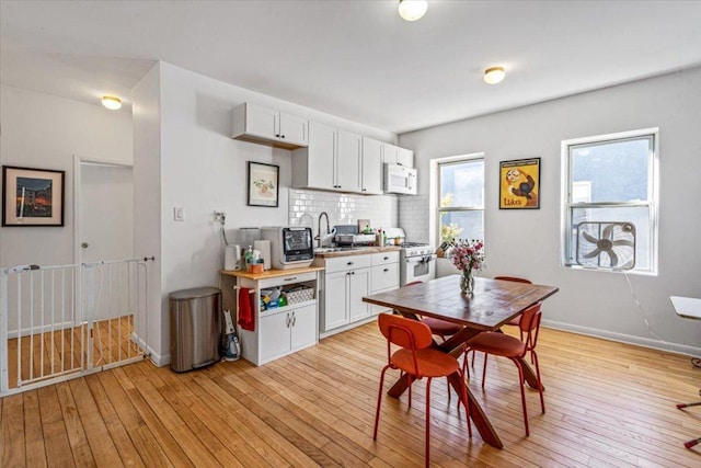 kitchen featuring white cabinets, backsplash, white appliances, and light hardwood / wood-style floors