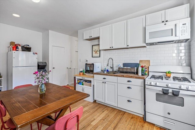 kitchen featuring white appliances, white cabinets, sink, backsplash, and light hardwood / wood-style flooring