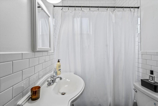 bathroom featuring sink, a shower with curtain, toilet, and tile walls