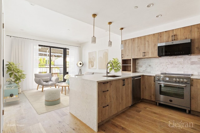 kitchen featuring kitchen peninsula, stainless steel appliances, pendant lighting, light hardwood / wood-style flooring, and sink