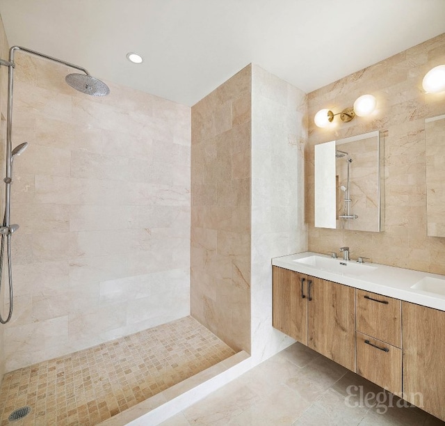 bathroom featuring tile walls, tiled shower, vanity, and tile patterned flooring