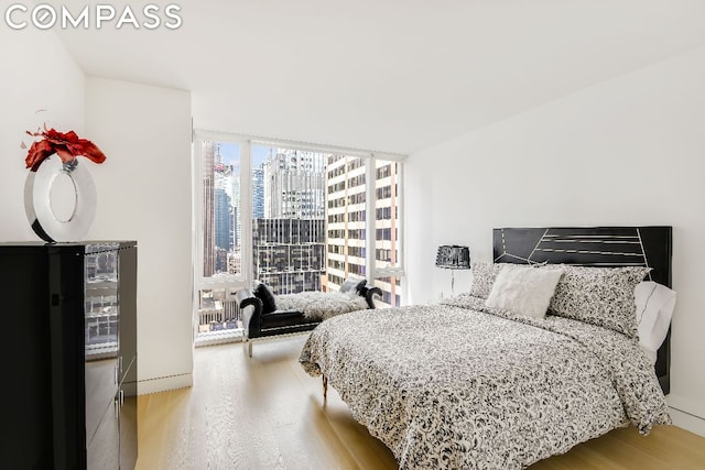 bedroom featuring a wall of windows and light hardwood / wood-style flooring