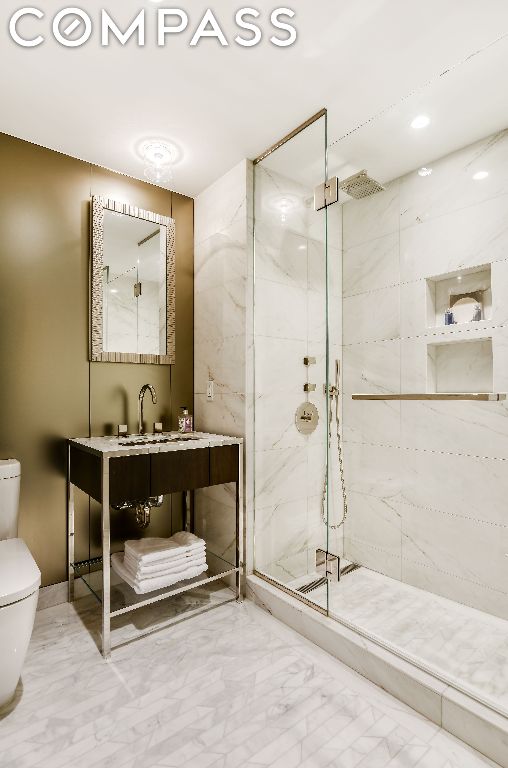 bathroom featuring toilet, a shower with door, and vanity