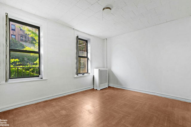 empty room featuring radiator, plenty of natural light, and baseboards