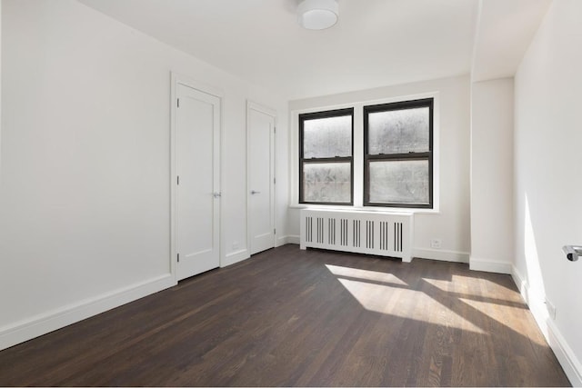 unfurnished bedroom with dark wood-type flooring and radiator heating unit