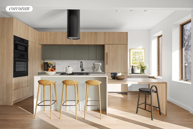 kitchen with light countertops, visible vents, modern cabinets, light wood-type flooring, and a kitchen bar