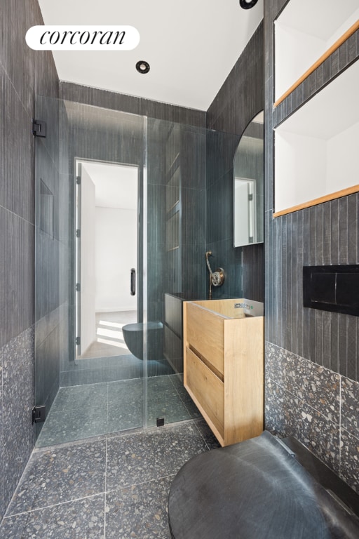 bathroom with tile walls, an enclosed shower, and vanity