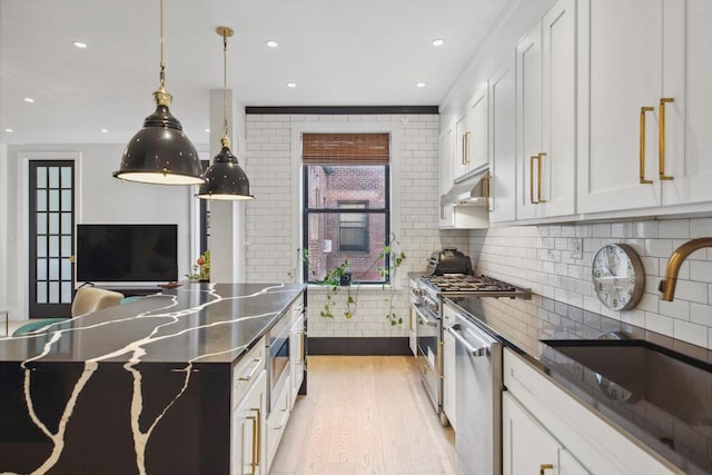 kitchen with sink, backsplash, white cabinets, and appliances with stainless steel finishes