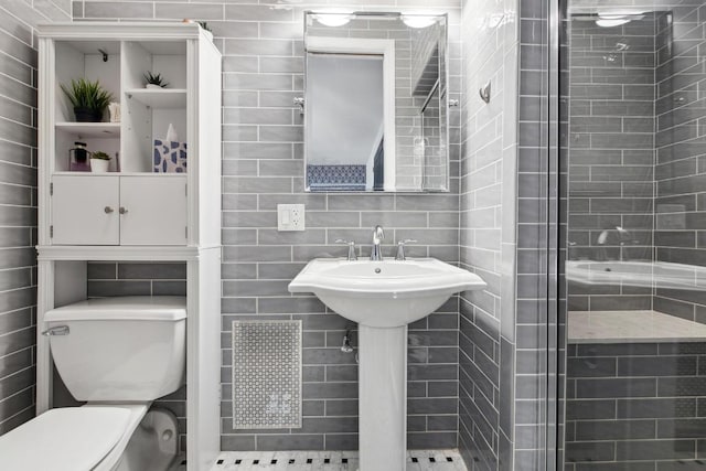 bathroom featuring tile walls, a shower with shower door, and toilet