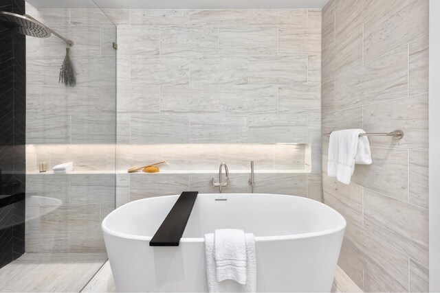 bathroom featuring a freestanding tub, tile walls, and a tile shower