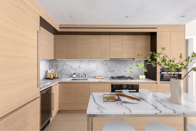 kitchen with light brown cabinetry, a sink, modern cabinets, beverage cooler, and black oven