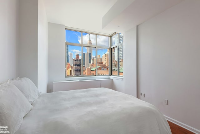 bedroom featuring a city view, baseboards, and wood finished floors