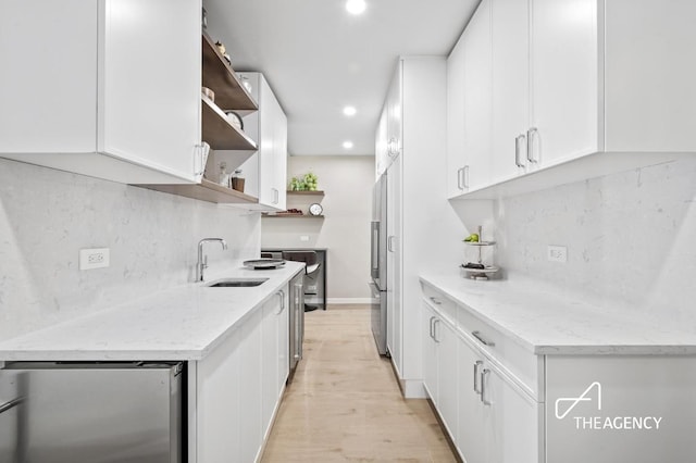 kitchen featuring open shelves, light stone counters, a sink, and white cabinets