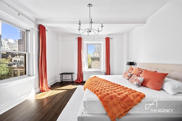 bedroom with a city view, dark wood finished floors, a notable chandelier, and multiple windows