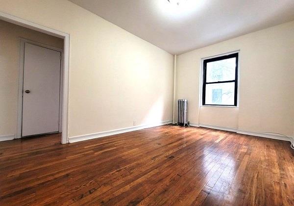 empty room with dark wood-type flooring and radiator heating unit