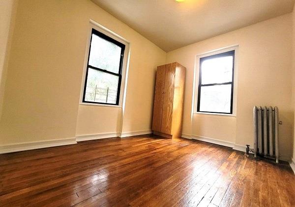 spare room featuring dark hardwood / wood-style floors and radiator heating unit