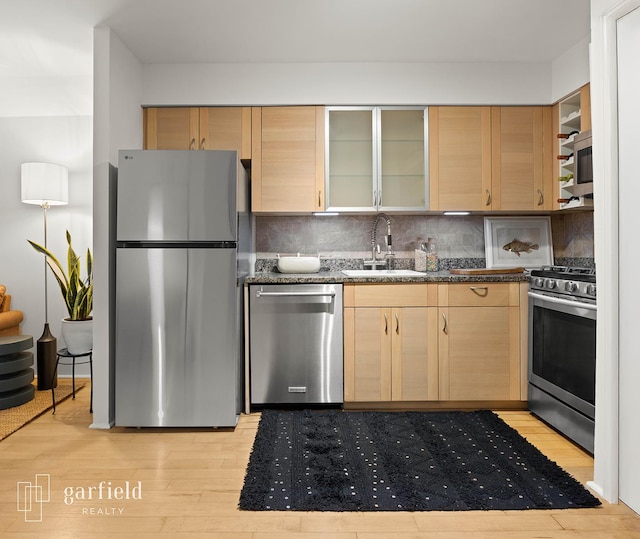 137 Bay Ridge Pkwy Unit 1, New York City, NY 11209 - kitchen featuring stainless steel appliances, light wood finished floors, tasteful backsplash, and glass insert cabinets