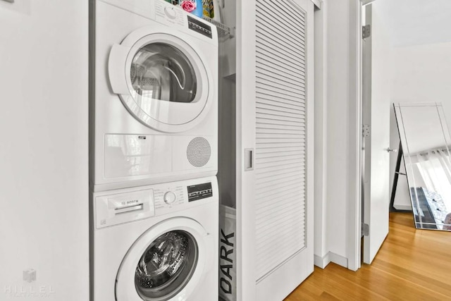 washroom with stacked washer and dryer and hardwood / wood-style flooring