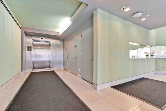corridor with elevator and tile patterned flooring