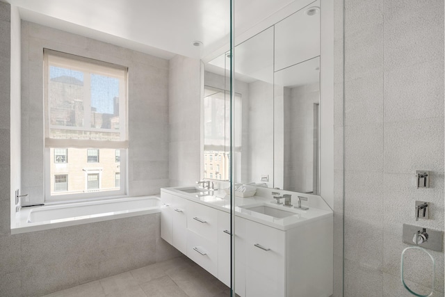 bathroom with a wealth of natural light, tile patterned flooring, tile walls, and a sink