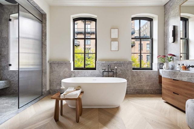 bathroom featuring vanity, parquet flooring, a washtub, and tile walls