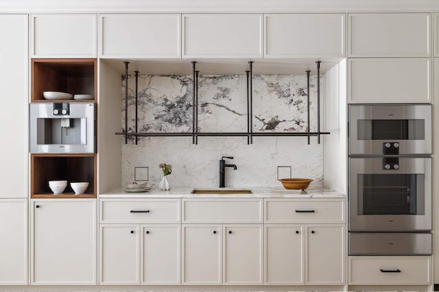 bar with light stone countertops, sink, stainless steel double oven, and decorative backsplash