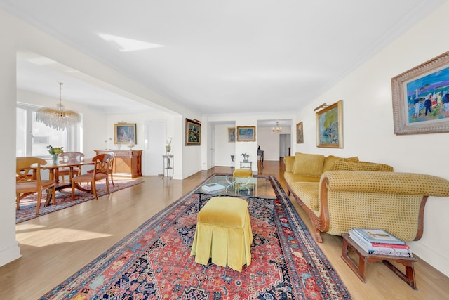 living area with baseboards, crown molding, wood finished floors, and a chandelier