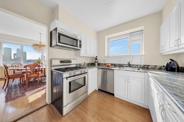 45 Sutton Pl S Unit 14F, New York City, NY 10022 - kitchen with an inviting chandelier, light wood-type flooring, white cabinetry, a sink, and stainless steel appliances