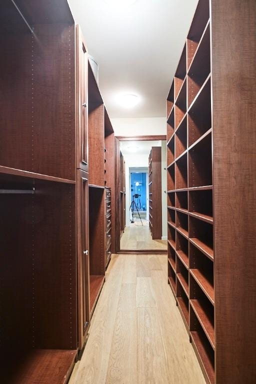 walk in closet with light hardwood / wood-style floors