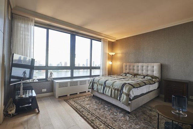 bedroom featuring hardwood / wood-style flooring, ornamental molding, radiator heating unit, and multiple windows