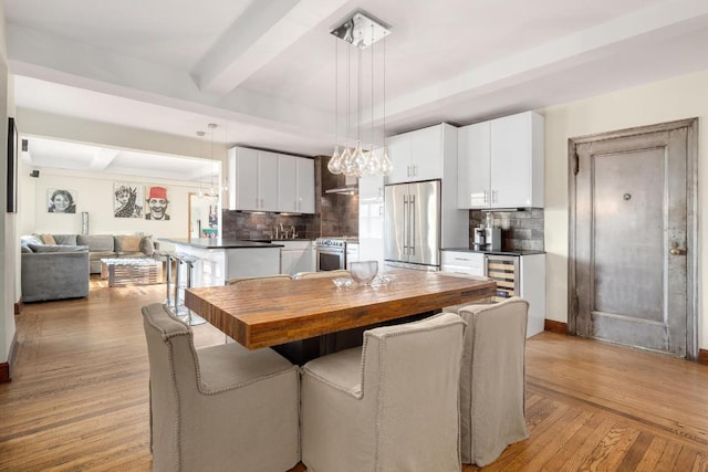 dining area with beam ceiling and light wood-style flooring