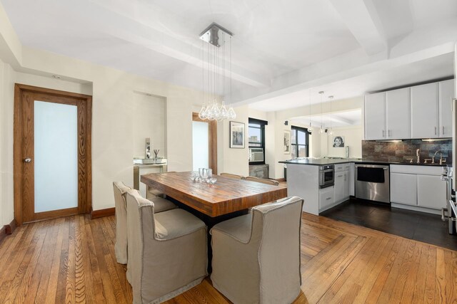 dining space featuring beamed ceiling and light hardwood / wood-style flooring