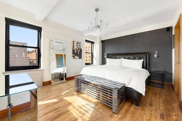 bedroom featuring an inviting chandelier, beamed ceiling, and light wood-type flooring