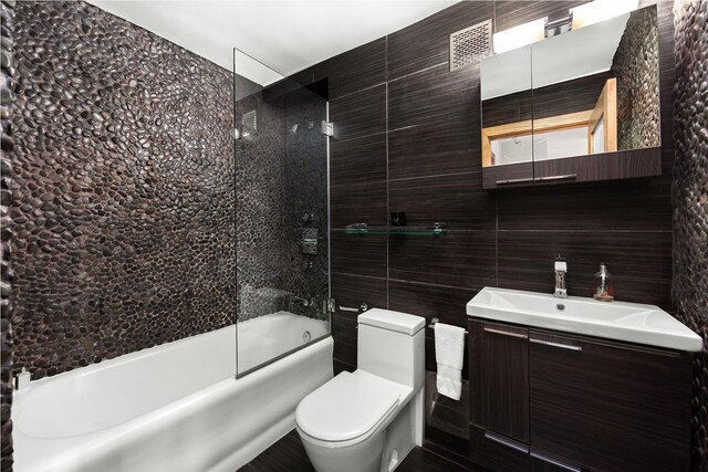 bathroom featuring toilet, vanity, and a shower with shower door