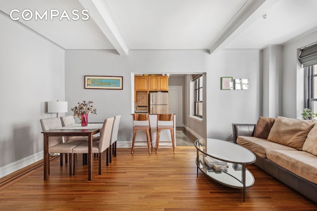 living room with beamed ceiling, baseboards, and light wood finished floors