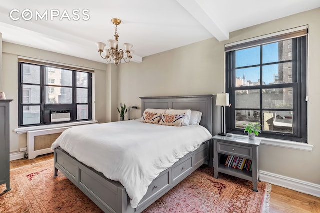 bedroom with beam ceiling, light wood-style flooring, baseboards, and a chandelier