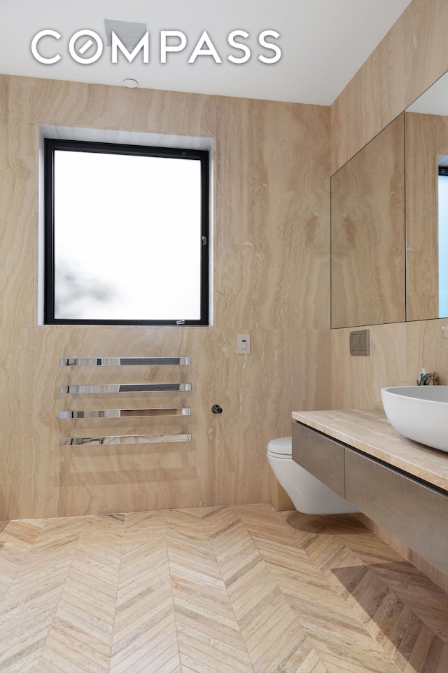 bathroom with toilet, tile walls, and vanity