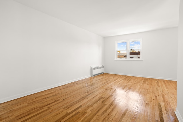 unfurnished room with radiator heating unit and light hardwood / wood-style flooring