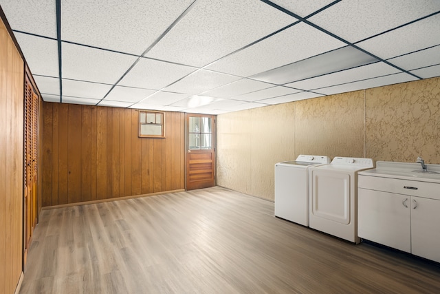 laundry room with wood-type flooring, independent washer and dryer, and wooden walls