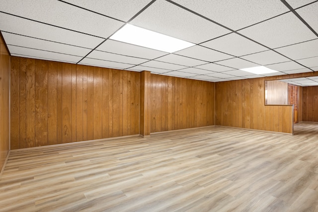 basement with light hardwood / wood-style floors and wooden walls