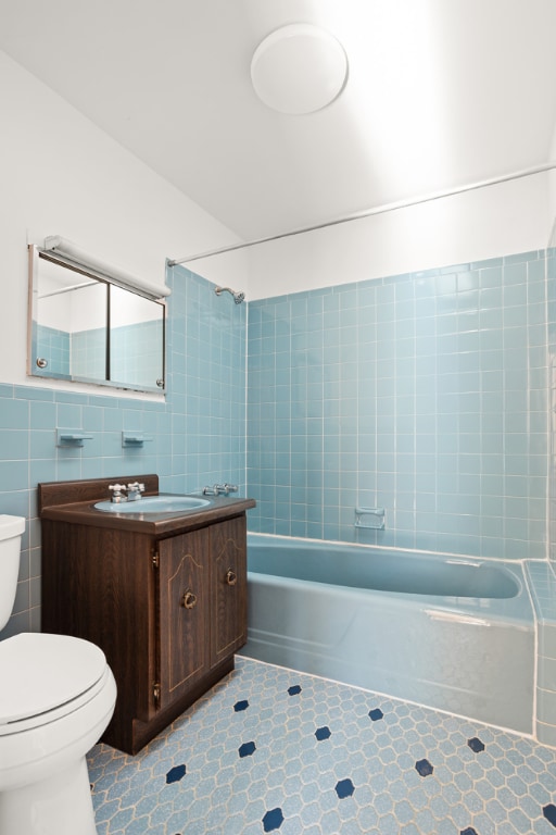 full bathroom with toilet, vanity, tile patterned flooring, tile walls, and tiled shower / bath combo