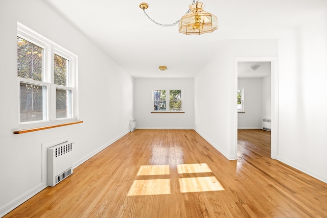 spare room with radiator heating unit and light hardwood / wood-style floors