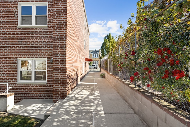 view of side of property featuring brick siding and fence