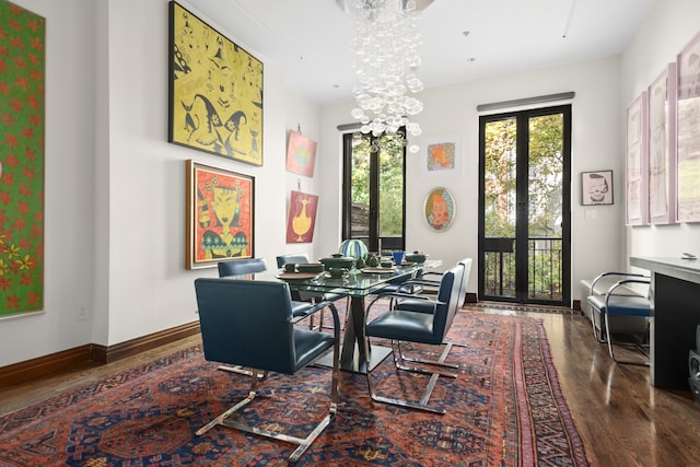 dining space with french doors, a notable chandelier, baseboards, and wood finished floors