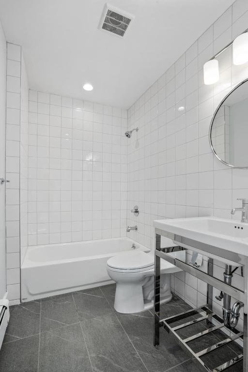 full bath featuring tile patterned flooring, toilet, bathtub / shower combination, visible vents, and tile walls