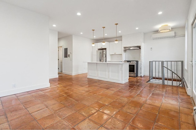 kitchen with pendant lighting, a wall unit AC, stainless steel appliances, light countertops, and a kitchen island with sink